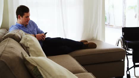 hombre discapacitado usando teléfono móvil en el sofá 4k