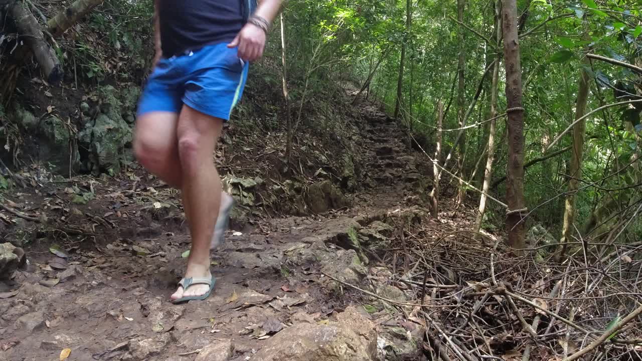 un excursionista masculino pasa por una cámara de bajo ángulo en el sendero de la selva tropical de piedra