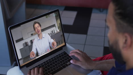 hombre de oriente medio teniendo una videollamada con un colega de oficina masculino en una computadora portátil