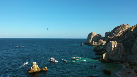 Birds-and-boats-on-the-rocky-coast-of-Cabo-San-Lucas,-Mexico---Static-drone-shot