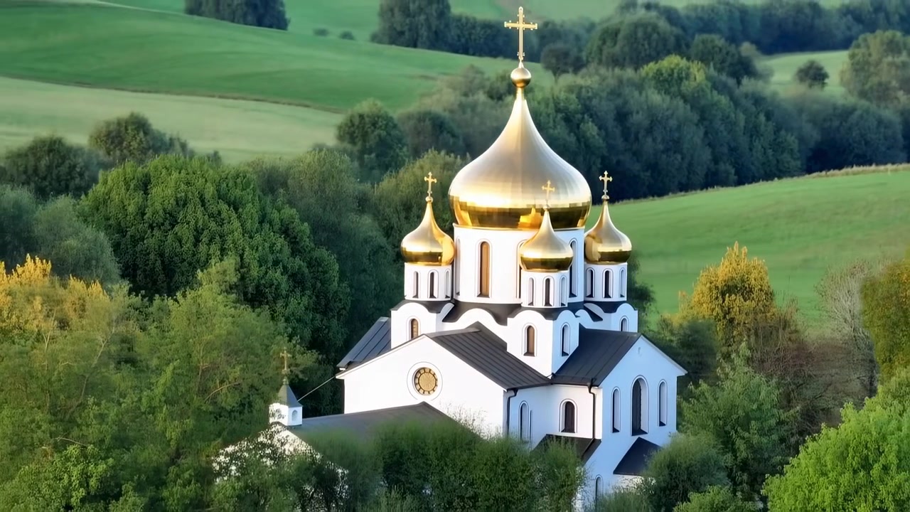 Вид с воздуха на безмятежную и мирную каменную церковь, расположенную в пышном зеленом ландшафте с деревьями и холмами. Спокойная обстановка подчеркивает архитектурную красоту православной церкви.