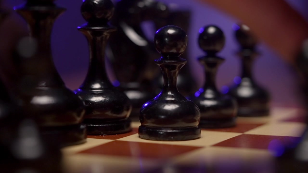 Une main déplace un pion d'échecs noir sur un échiquier en bois