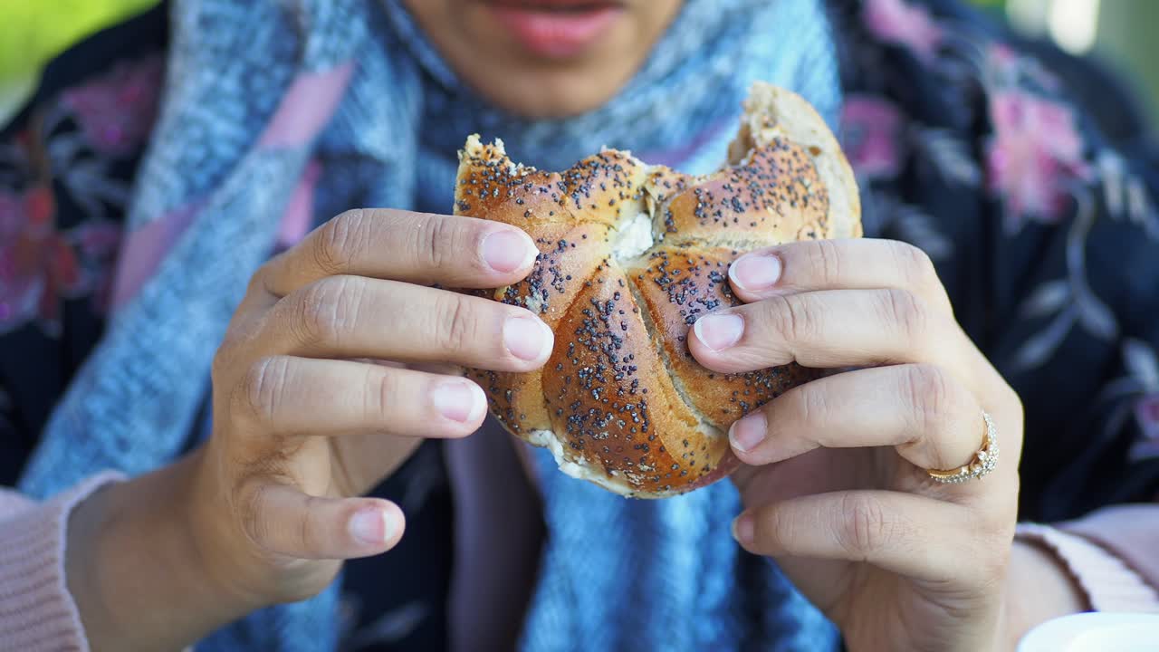 mujer comiendo un bagel de semillas de amapola