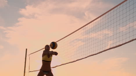 An-Einem-Schönen-Sommerabend-Springt-Ein-Sportliches-Mädchen-Beim-Beachvolleyball-In-Die-Luft-Und-Schlägt-Den-Ball-über-Das-Netz.-Eine-Kaukasische-Frau-Erzielt-Einen-Punkt.