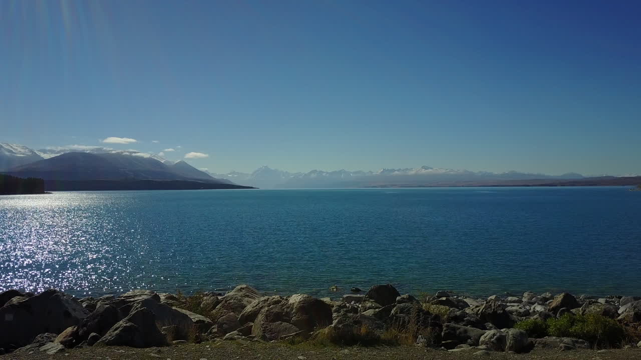 el dron aterriza en la orilla del lago pukaki con el monte cook en la distancia.