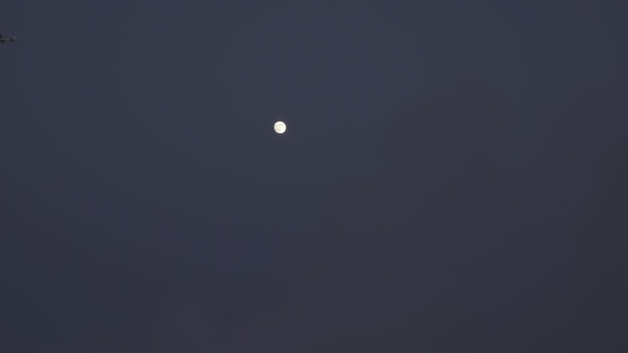 보름달 위를 날아다니는 작은 비행기