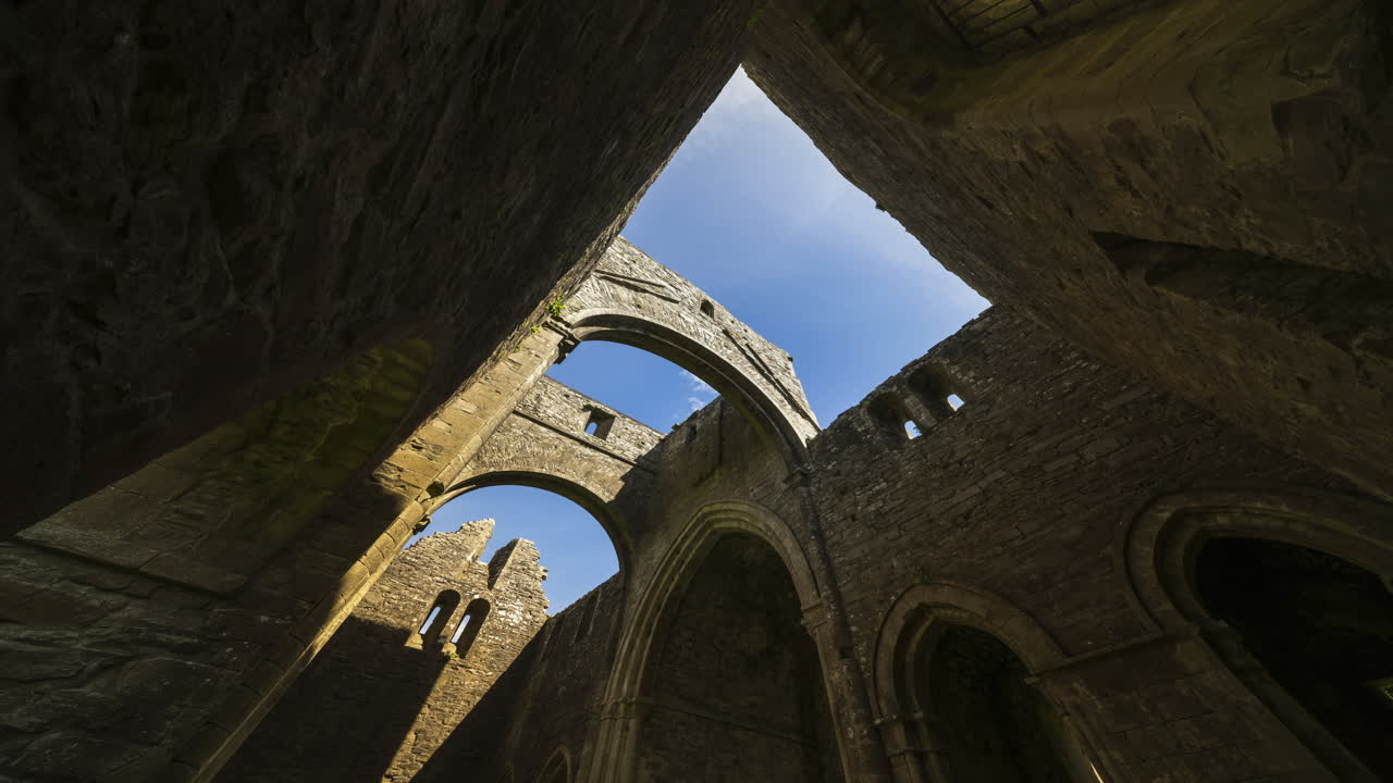 Motion time lapse of Boyle Abbey medieval ruin in county Roscommon in Ireland as a historical sightseeing landmark with clouds in the sky on a summer day