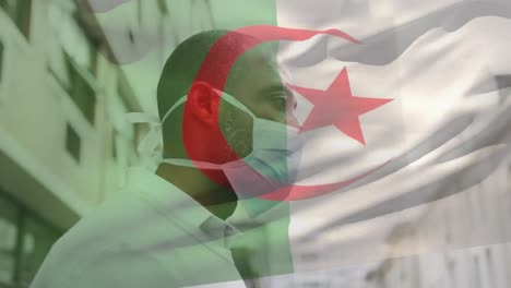 Animation-of-flag-of-algeria-waving-over-man-wearing-face-mask-during-covid-19-pandemic