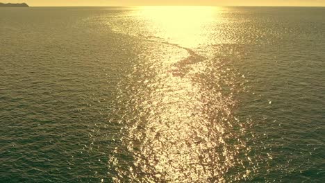 aerial view over the ocean with sunlit reflection in warm light in the philippines