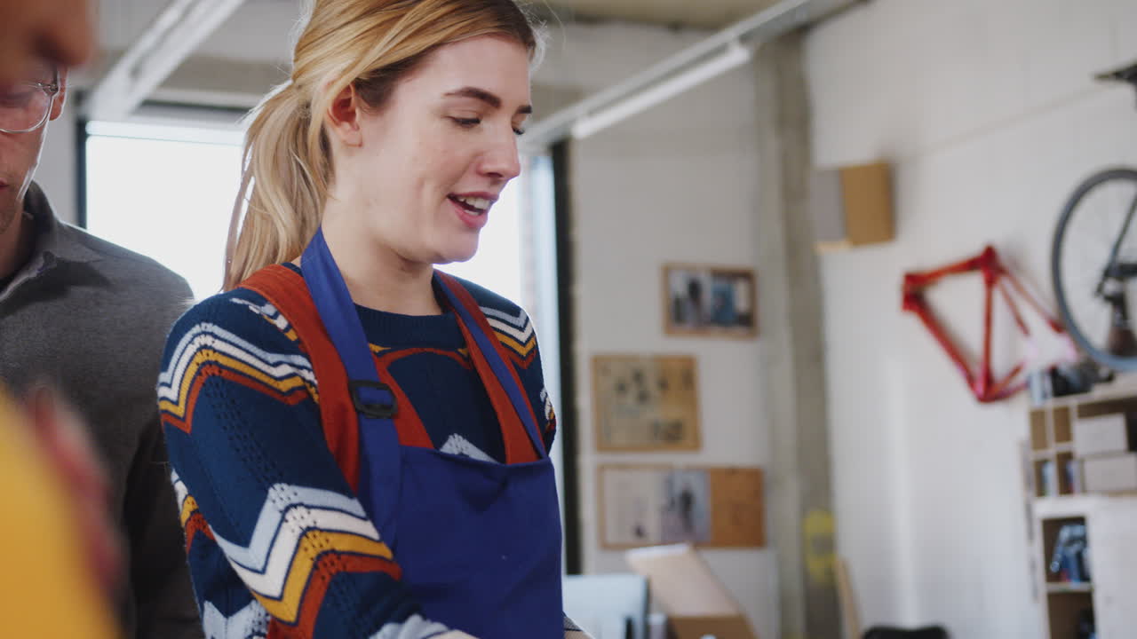 gruppo di apprendiste in laboratorio che imparano a usare utensili elettrici per assemblare biciclette