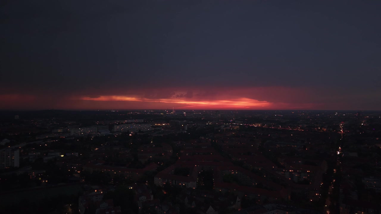 Město s viditelným úderem blesku proti bouřkové obloze, osvětlující městskou krajinu v noci. Nejlepší letecký panoramatický pohled dronem.