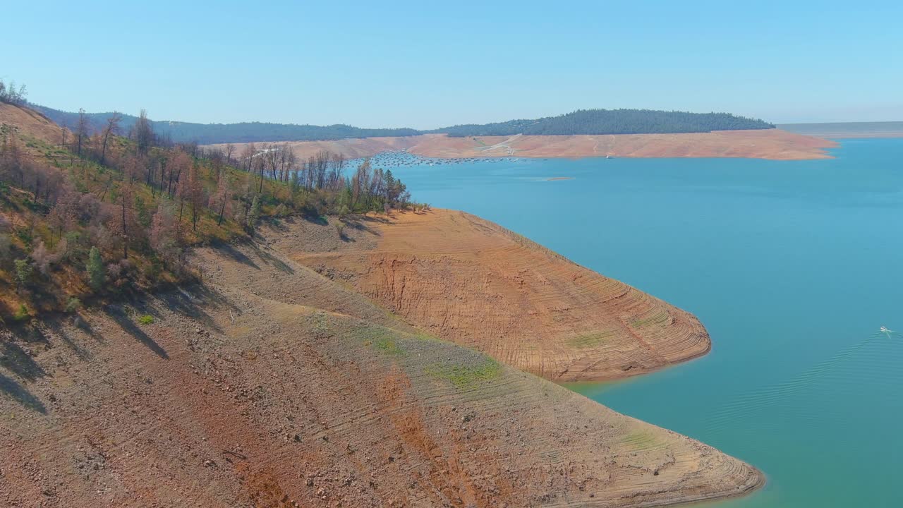 asombrosa antena sobre el lago oroville de california asolado por la sequía con bajos niveles de agua, costa en retroceso y árboles y bosques quemados
