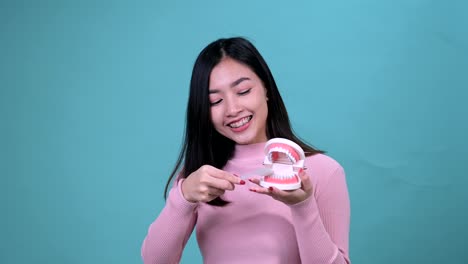 푸른 스크린 배경에 정형 치과 장치를 착용 한 미소 짓는 아시아 여성. 치과 관리와 건강한 치아.
