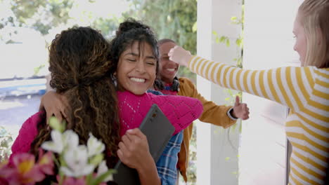 happy diverse group of teenage friends greeting and embracing at door at home, slow motion