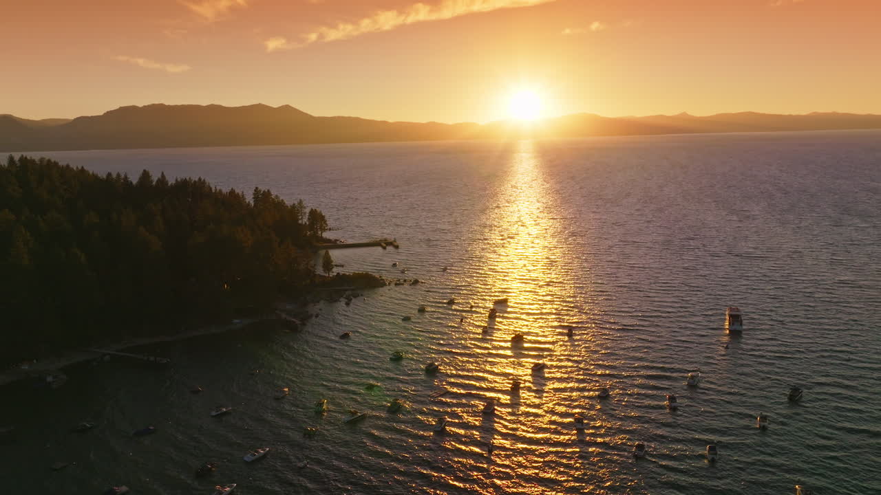 Diverse boats holding still on the surface of Lake Tahoe, California, USA. Beautiful scenery of sunset over the lake and mountains.