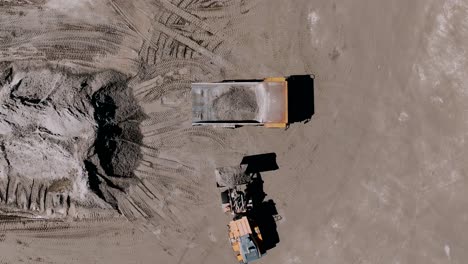 aerial overhead shot of an excavator loading sand into a haul truck