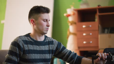 man adjusting camera equipment in workshop or studio, focusing on device controls, preparing for filming. close-up of hands handling camera, surrounded by storage boxes and green walls