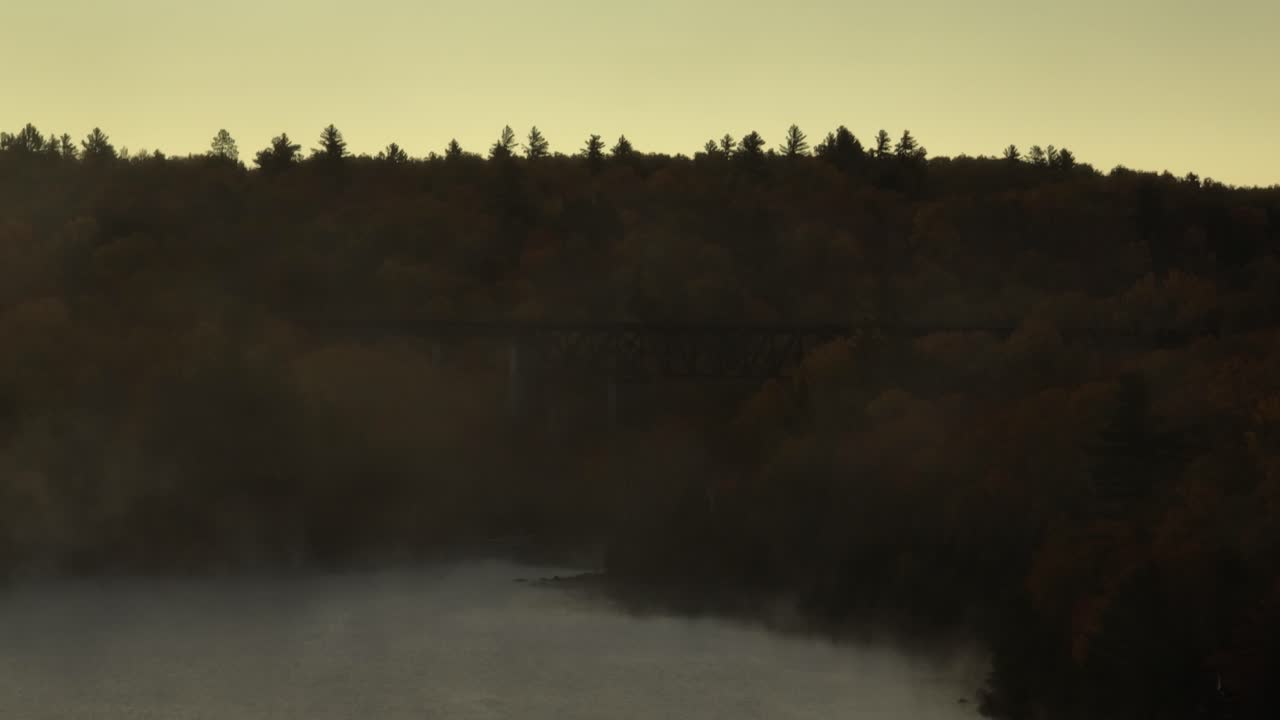 vista aérea de ángulo bajo del puente de caballetes onawa a través de la niebla matutina