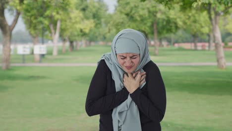 sick muslim woman having a heart attack in park