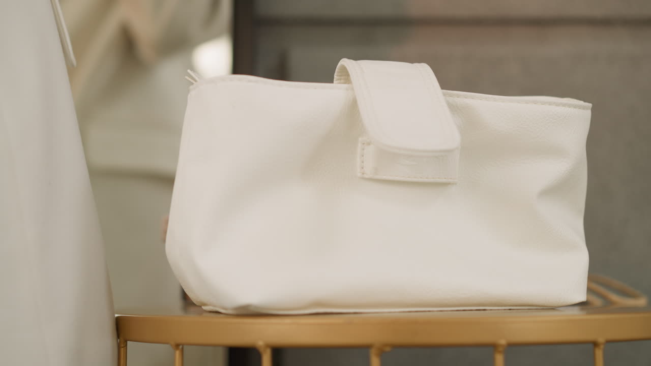 Mano di donna che appoggia una piccola borsa fatta di materiale di qualità.