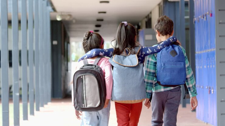 En la escuela, tres jóvenes estudiantes birraciales están caminando juntos