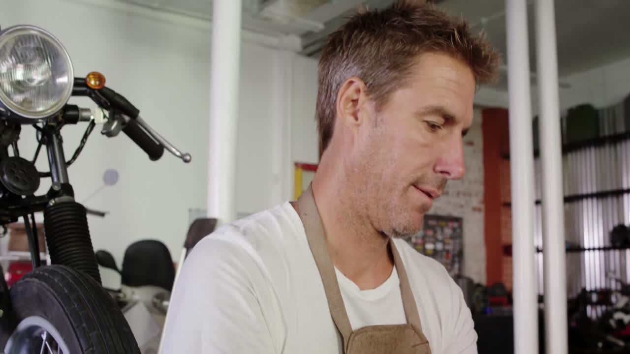 механик, использующий цифровой планшет в гараже по ремонту мотоциклов 4k