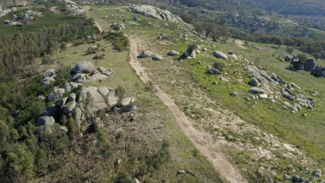 Ciclistas-De-Montaña-Recorriendo-Un-Sendero-De-Tierra-Ventoso-En-Minho,-Norte-De-Portugal---Tiro-De-Seguimiento-De-Seguimiento-De-Diapositivas-Aéreas