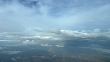 volando a través de un cielo turbulento con algunas nubes lluviosas por delante con un arco iris debajo de las nubes