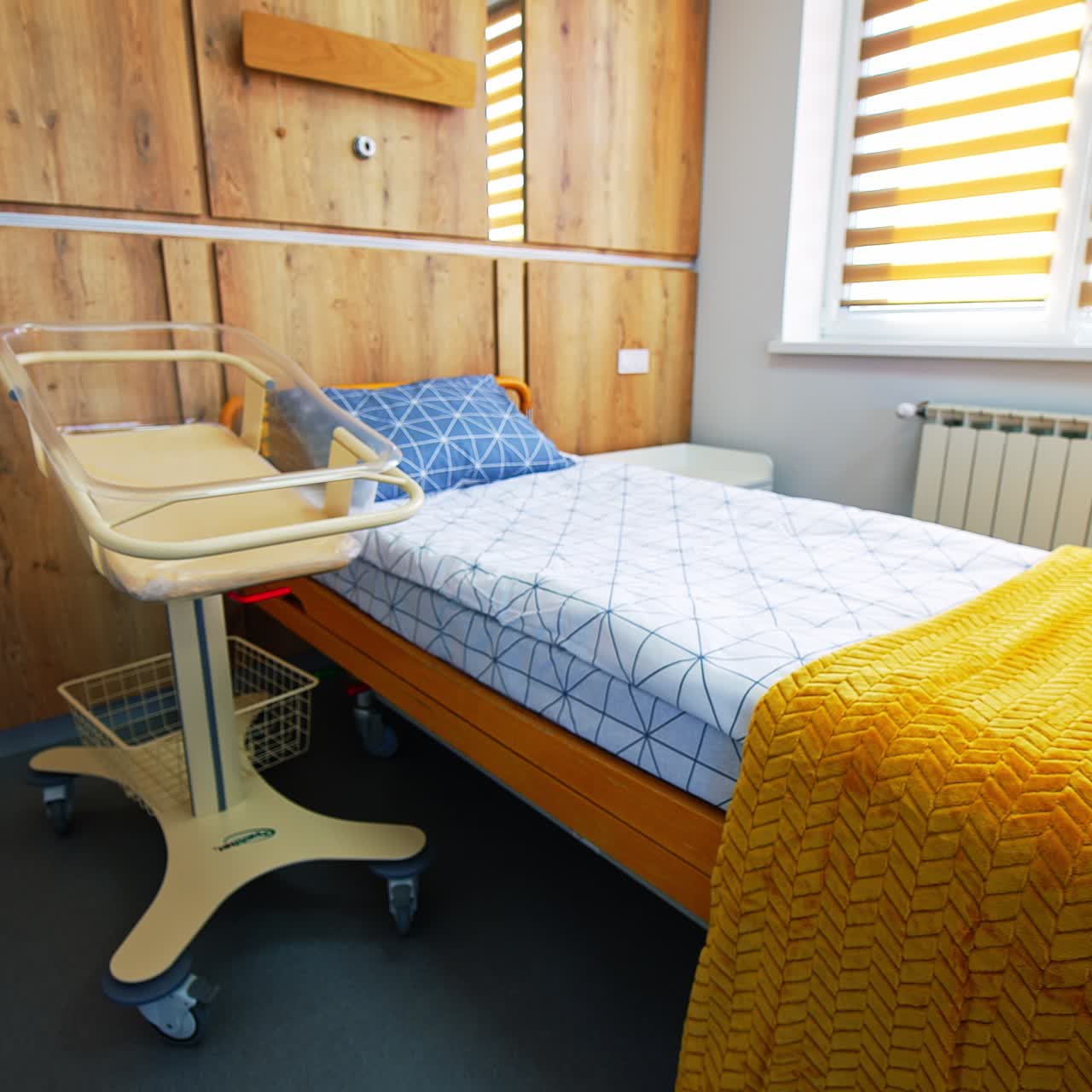 Modern design of a room for mother and newborn child. Comfortable bed with bright bedclothes and baby crib at bedside