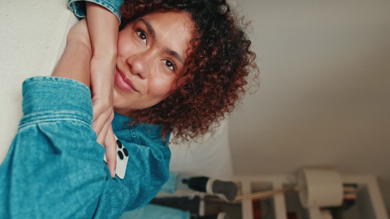 Relaxed Young Woman with Curly Hair Lying Down and Smiling