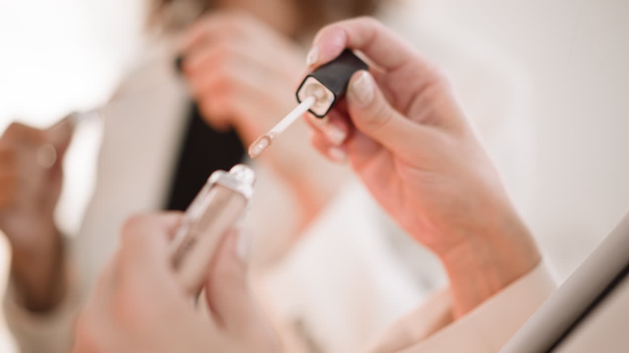 de las manos de la mujer desenrollando el corrector beige para aplicar bajo los ojos