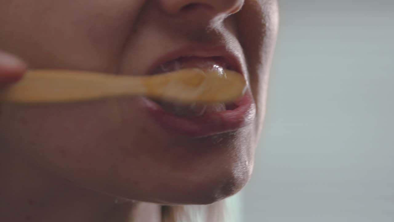 Woman brushing teeth with a biodegradable bamboo toothbrush