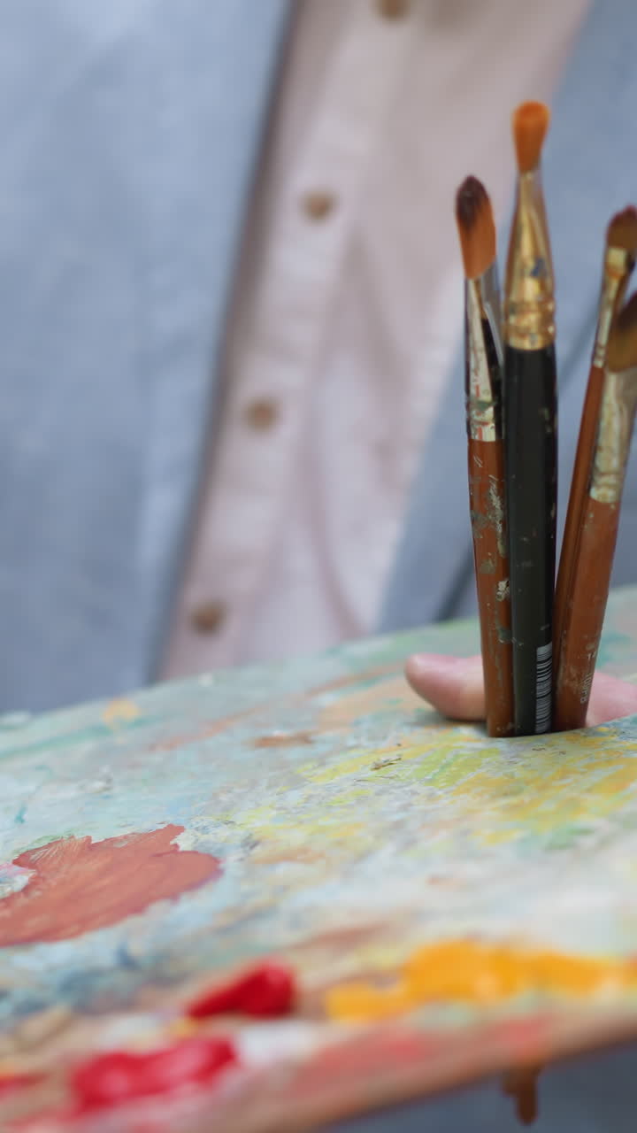 예술 제작자는 보드 클로즈업에서 분홍색을 혼합합니다. 크리에이티브 디자이너는 작업실에서 캔버스에 걸작을 그리기 위해 맛있는 페인트를 사용합니다. 작업 중인 화가.