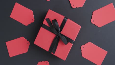 Video-of-gift-tags-with-red-gift-box-with-ribbon-and-copy-space-on-black-background