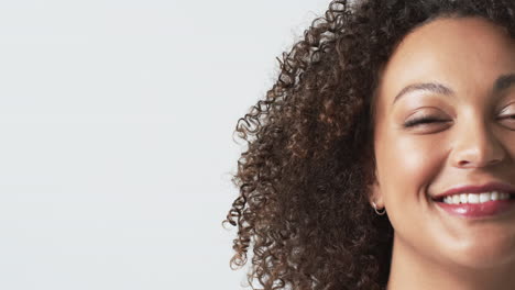 smiling plus size woman with curly hair showing only half of her face against white background, copy