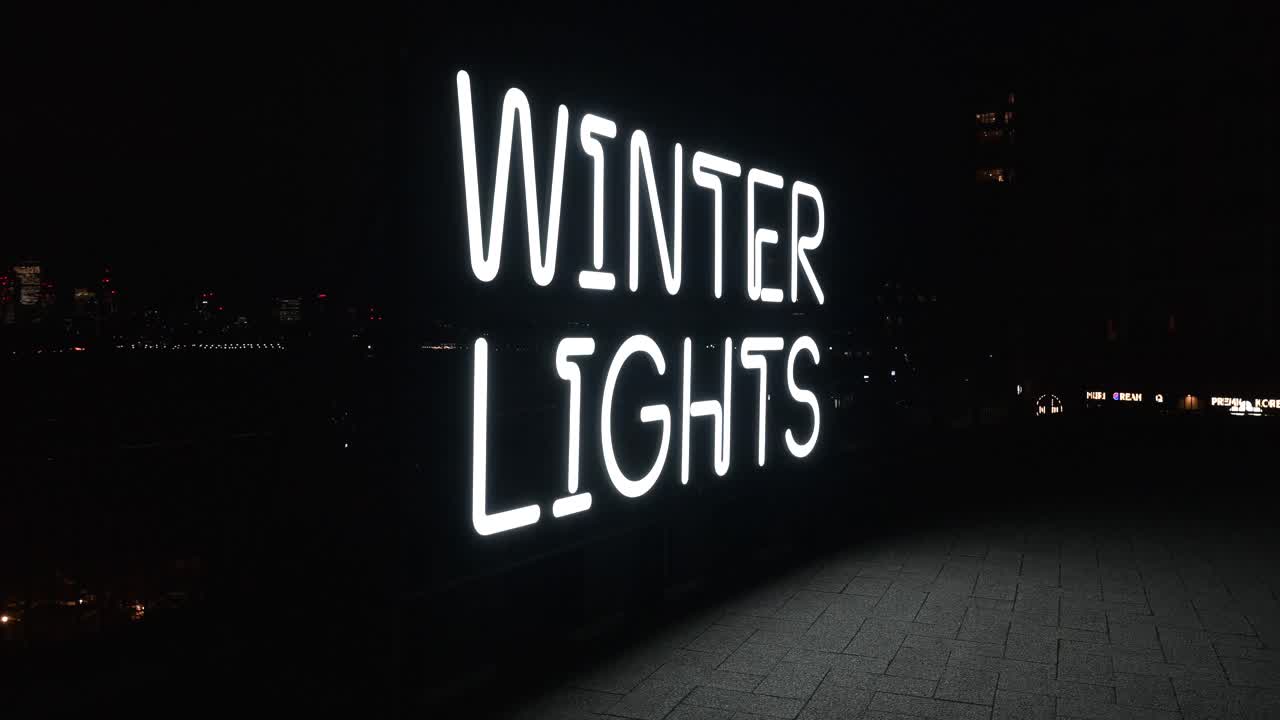 Percorso artistico illuminato a tema invernale con installazioni luminose e visitatori che passeggiano tra coloratissimi allestimenti illuminati di sera