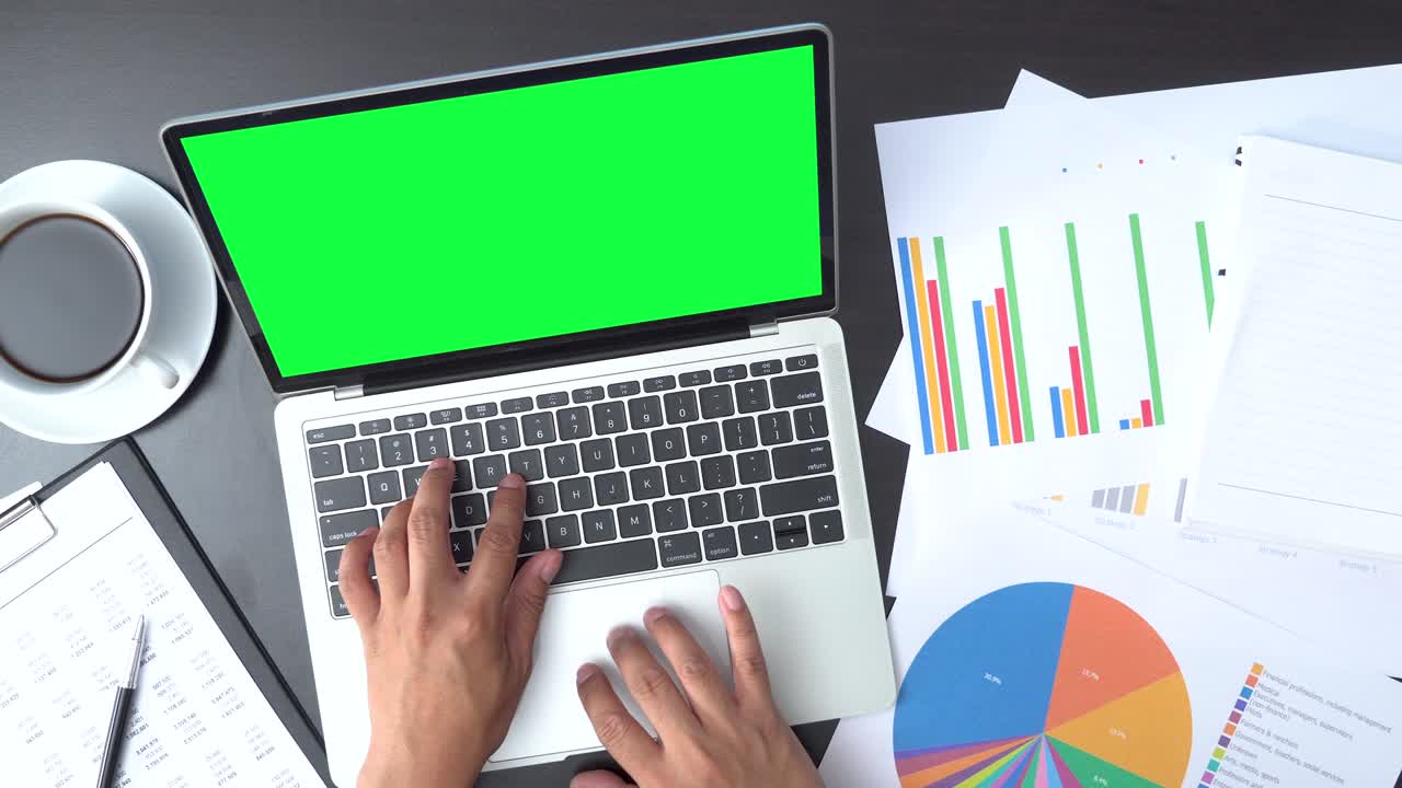 vista superior de un hombre de negocios trabajando con una computadora portátil de pantalla verde y documentos con gráficos y diagramas
