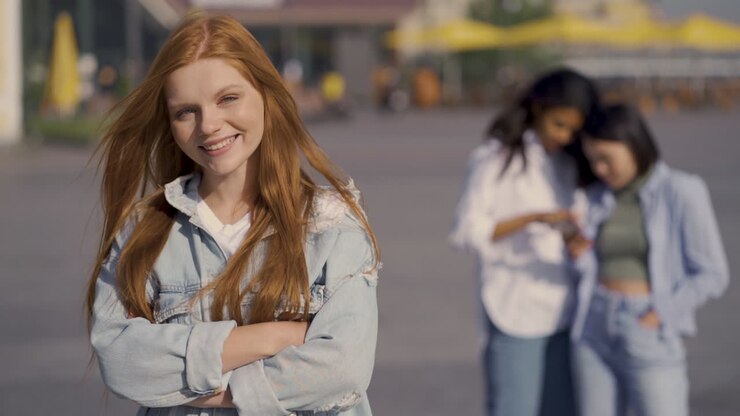 Giovane donna dai capelli rossi posa sorridendo alla macchina fotografica