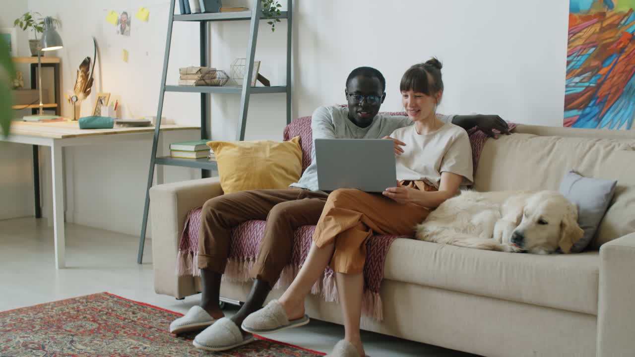 Multiethnic Family Couple Using Laptop and Talking in Living Room