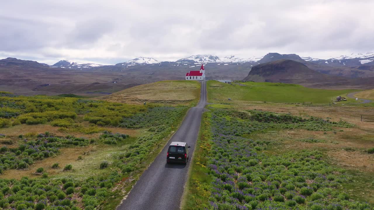 아이슬란드 산의 언덕에 있는 교회까지 운전하는 검은색 캠퍼 밴 위의 공중 1