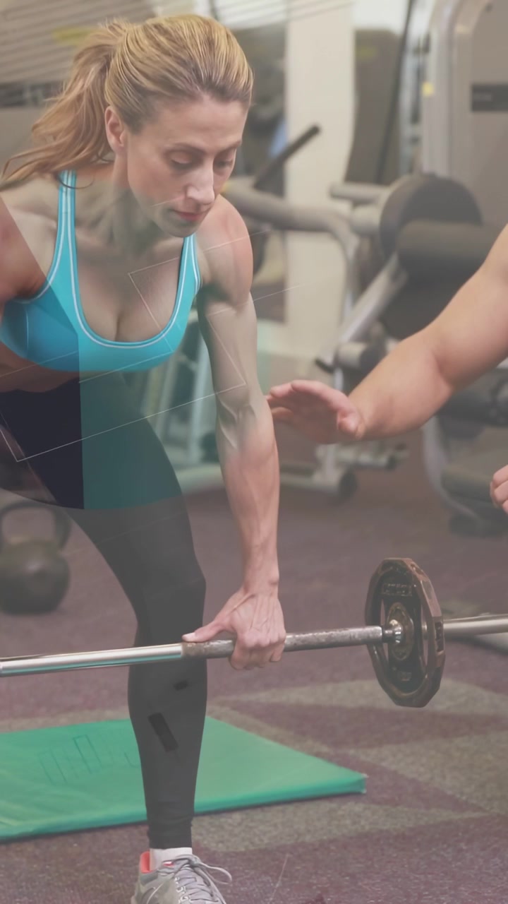 Vertikal video: Trainee närmar sig skivstång på gymmatta, tränare kliver fram och vägleder lyft för säkerhet