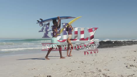 american flag waving over independence day text against couple carrying surfboards on the beach