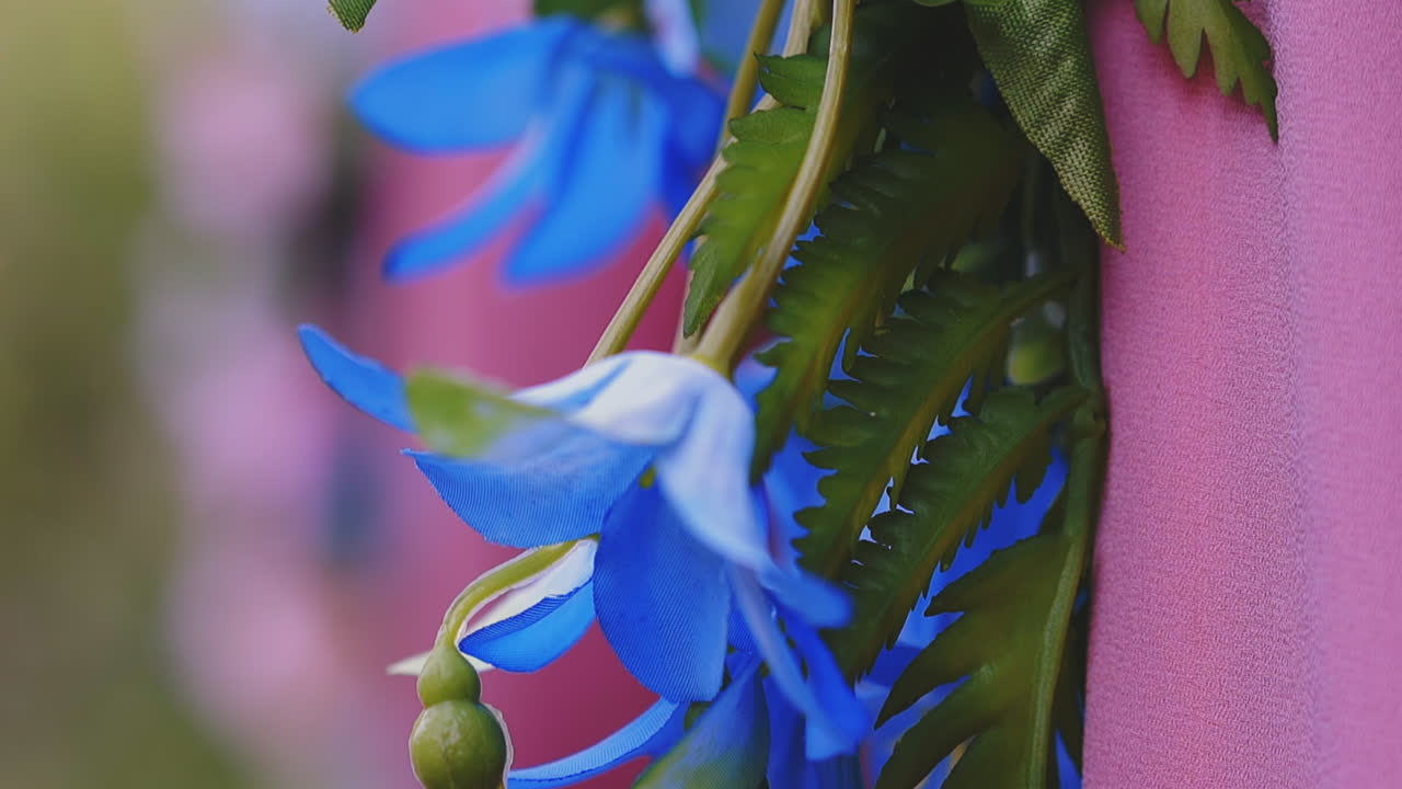 인공 꽃과 초록색 잎 근처의 분홍색 직물 클로즈업