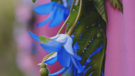 flores artificiales y hojas verdes cerca de un primer plano de tela rosa