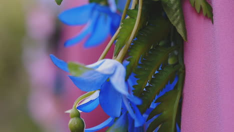 artificial flowers and green leaves near pink fabric closeup