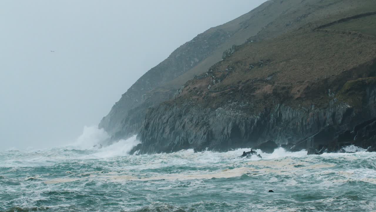 하늘에 갈매기가 있는 폭풍우 치는 아일랜드 해안에서 튀는 파도