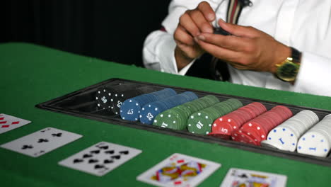 a poker dealer croupier in a casino counting and paying out chips to a winner at a black jack cards table