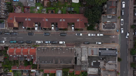 Aerial-birds-eye-overhead-top-down-panning-view-of-car-driving-in-narrow-town-streets-and-crossroads.-London,-UK