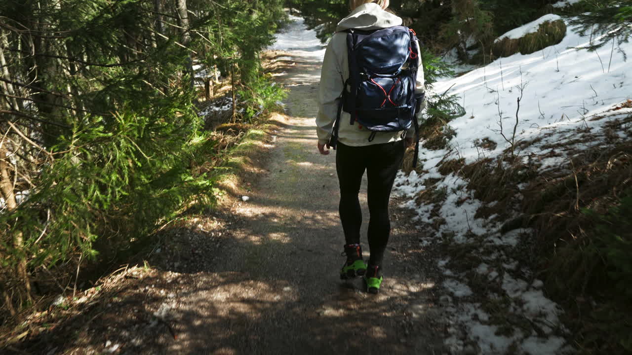 Active female trekking alone through a snowy forest. Slow motion