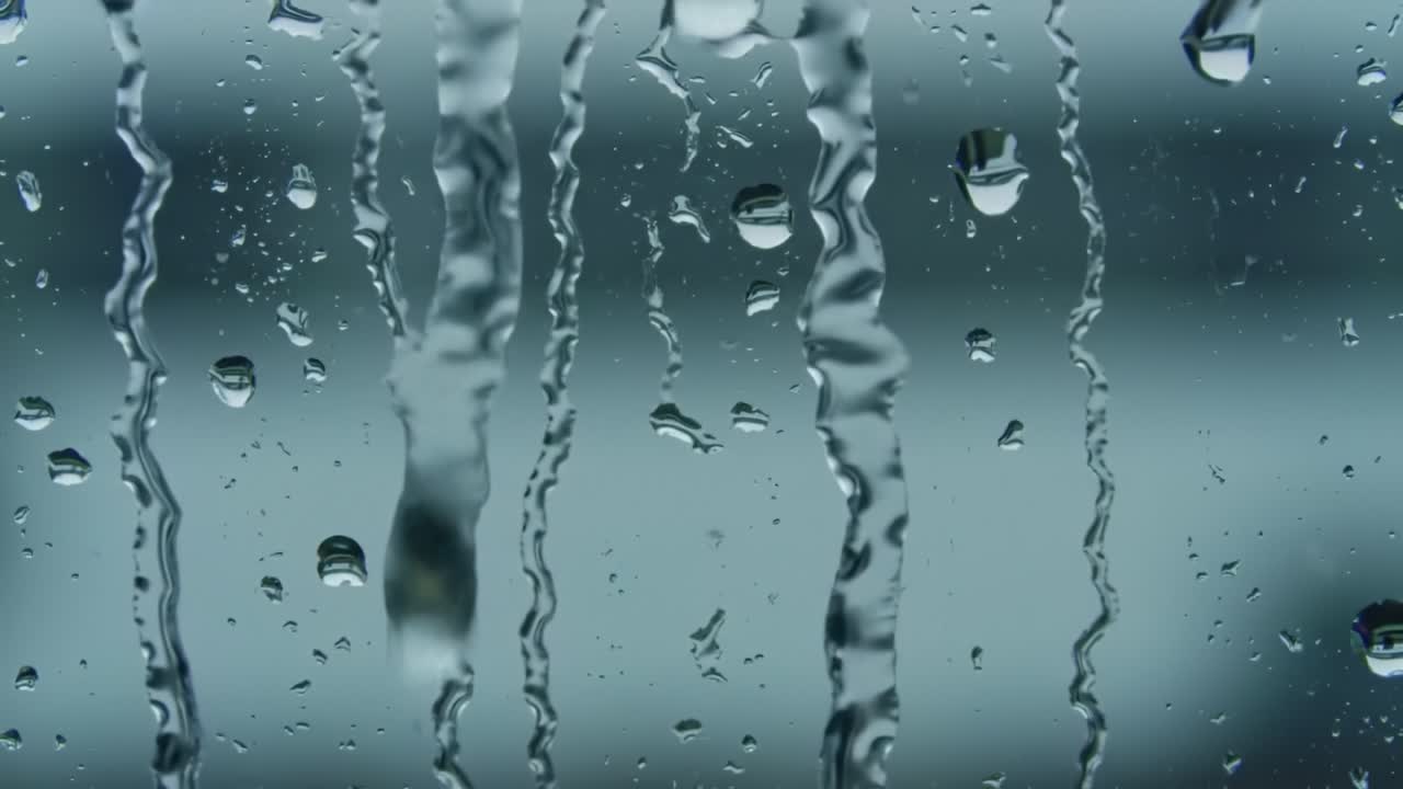 Rain droplets trickle down the glass, blurring the outside world. The calm sounds of rainfall create a soothing ambiance perfect for relaxation or reflection.